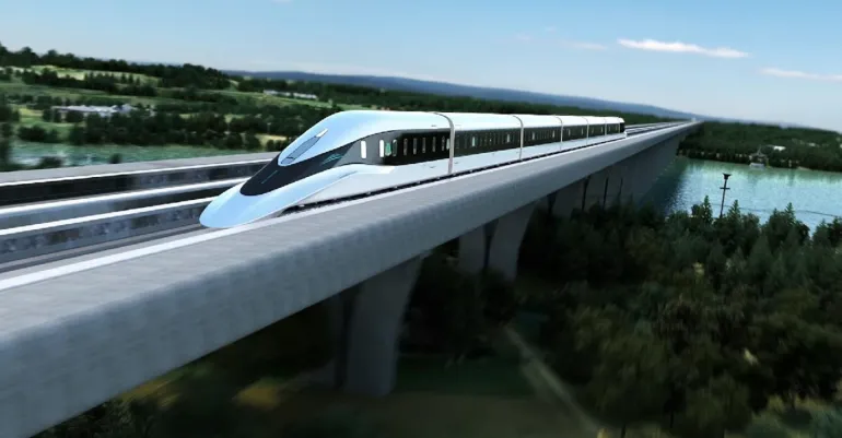 A white streamlined magnetic levitation train travelling at speed along an elevated guideway on a bridge crossing green countryside and a river